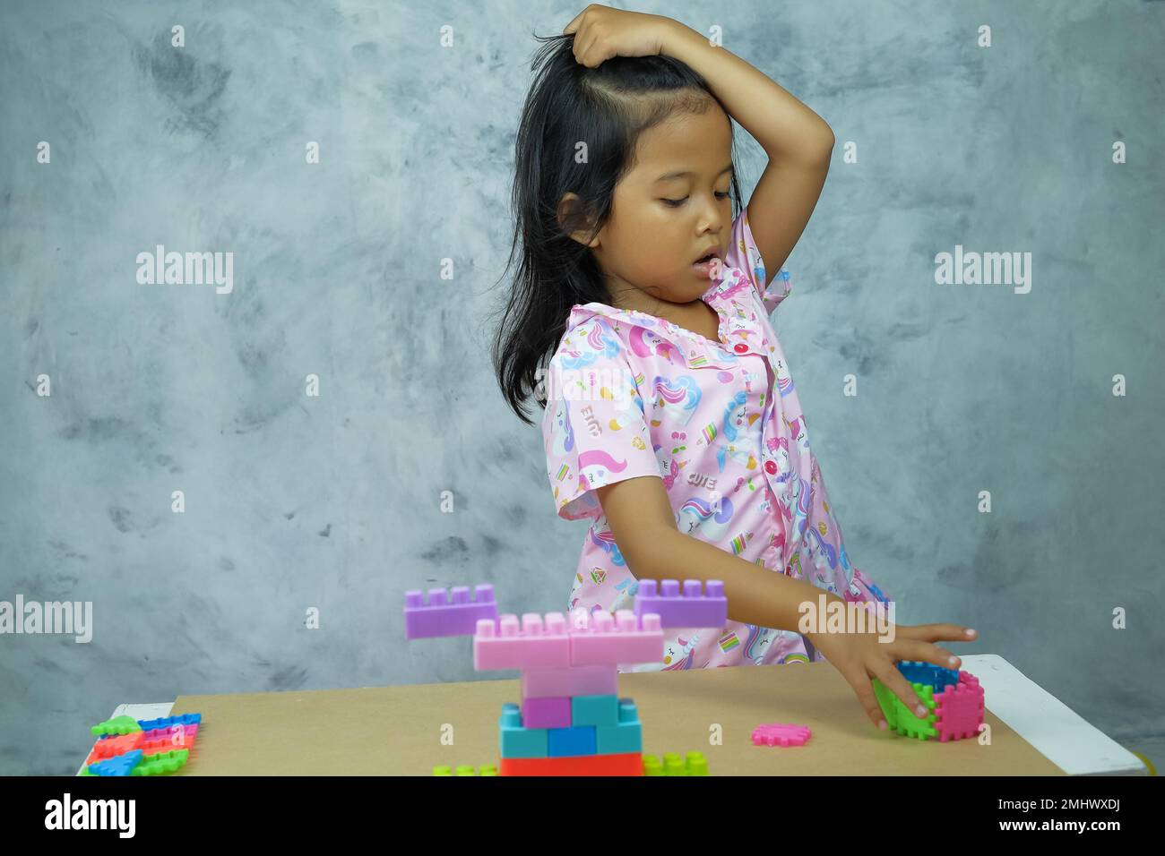 Un primo piano di una bambina del sud-est asiatico che gioca con colorati cubi di plastica Foto Stock