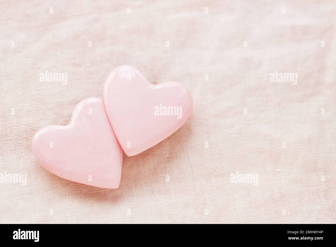 Due cuori rosa pastello su fondo di lino rosa. Decorazioni per San Valentino. Foto Stock