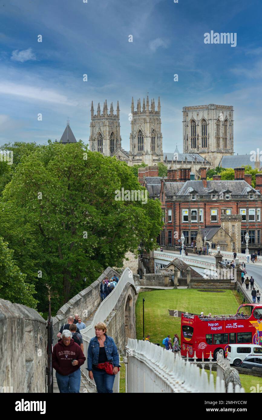 York Minster e Lendal Bridge con i turisti che si godono una passeggiata lungo le mura medievali romane di York, North Yorkshire, Regno Unito. Foto Stock