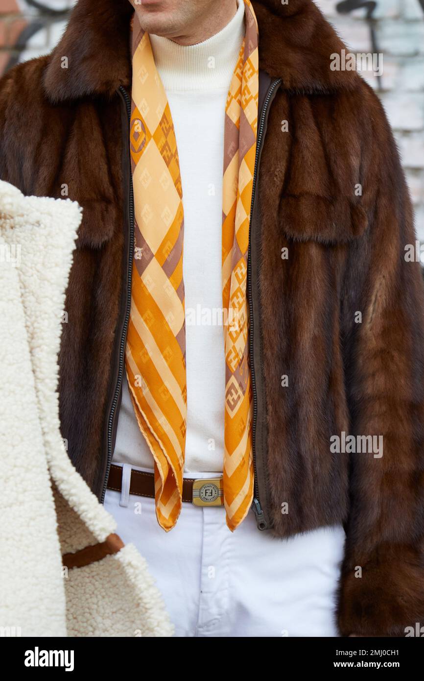 MILANO, ITALIA - 14 GENNAIO 2023: Uomo con giacca in pelliccia marrone e sciarpa e cintura gialla Fendi prima della sfilata di moda Fendi, Milano Fashion Week Street Style Foto Stock