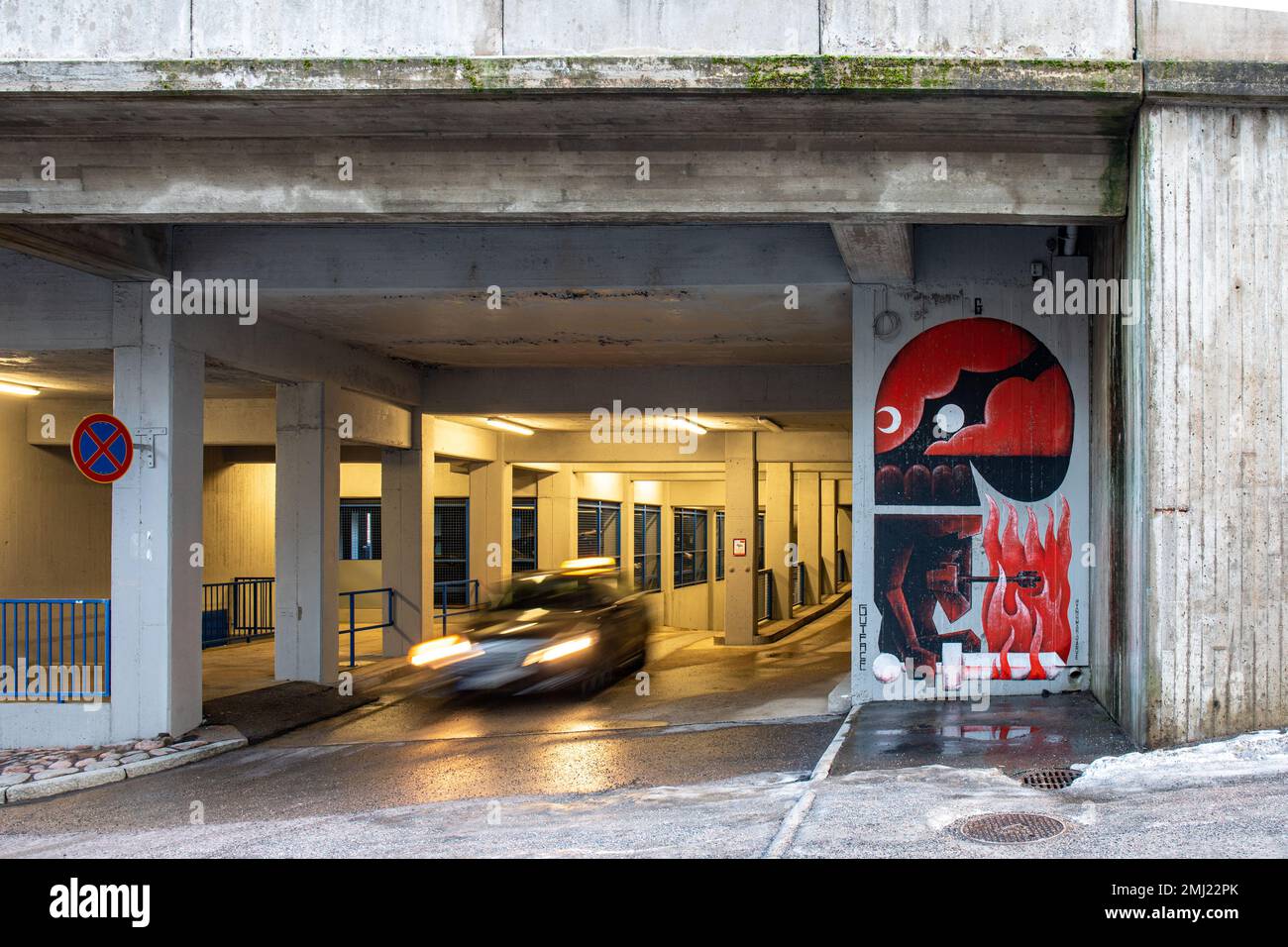 Movimento sfocato di un'auto che esce da un garage con graffiti murali dell'artista estone Gutface nel quartiere Itä-Pasila di Helsinki, Finlandia Foto Stock