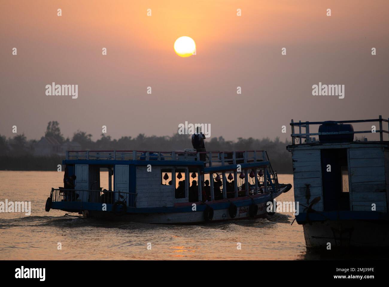 Uomo in barca di fronte al tramonto - Hoi An Vietnam Foto Stock