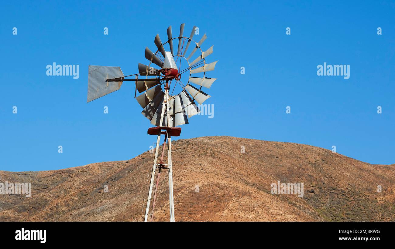 Turbina eolica, irrigazione, collina marrone, cielo azzurro, Vega Rio Las Palmas, interno dell'isola, Fuerteventura, Isole Canarie, Spagna Foto Stock