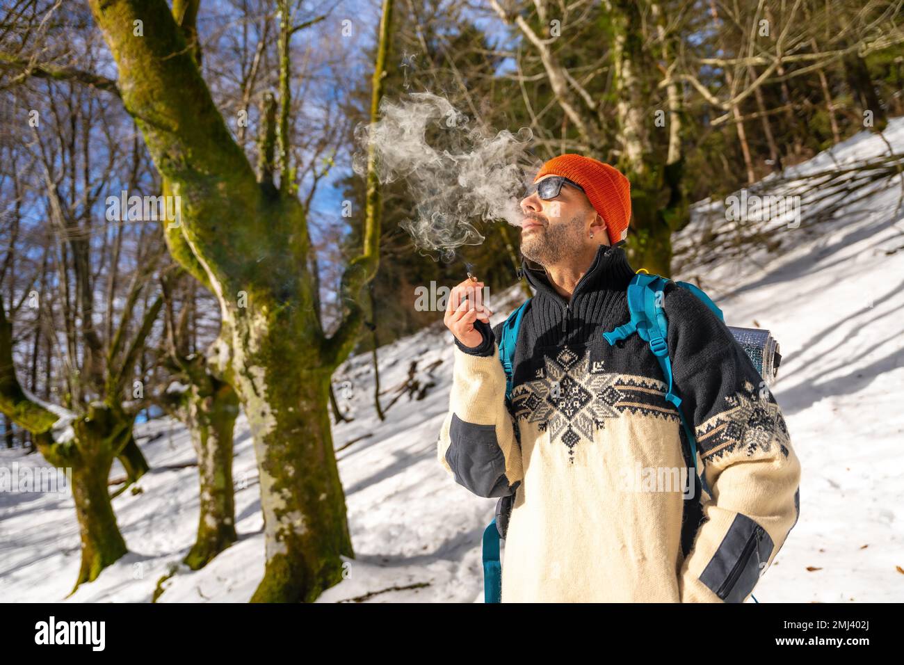Un uomo che fuma una sigaretta su una collina innevata in inverno Foto Stock