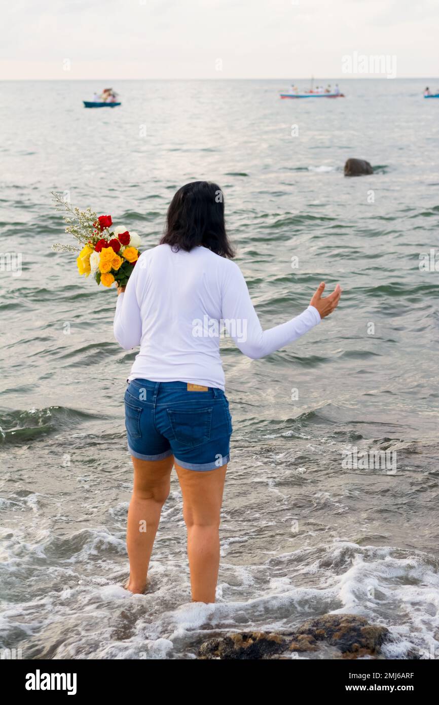 Salvador, Bahia, Brasile - 02 febbraio 2017: Una donna che ammira Candomble getta fiori in mare in onore di Iemanja il giorno della sua festa. Salvador, Foto Stock