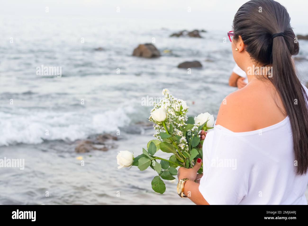 Salvador, Bahia, Brasile - 02 febbraio 2017: Una donna che ammira Candomble getta fiori in mare in onore di Iemanja il giorno della sua festa. Salvador, Foto Stock