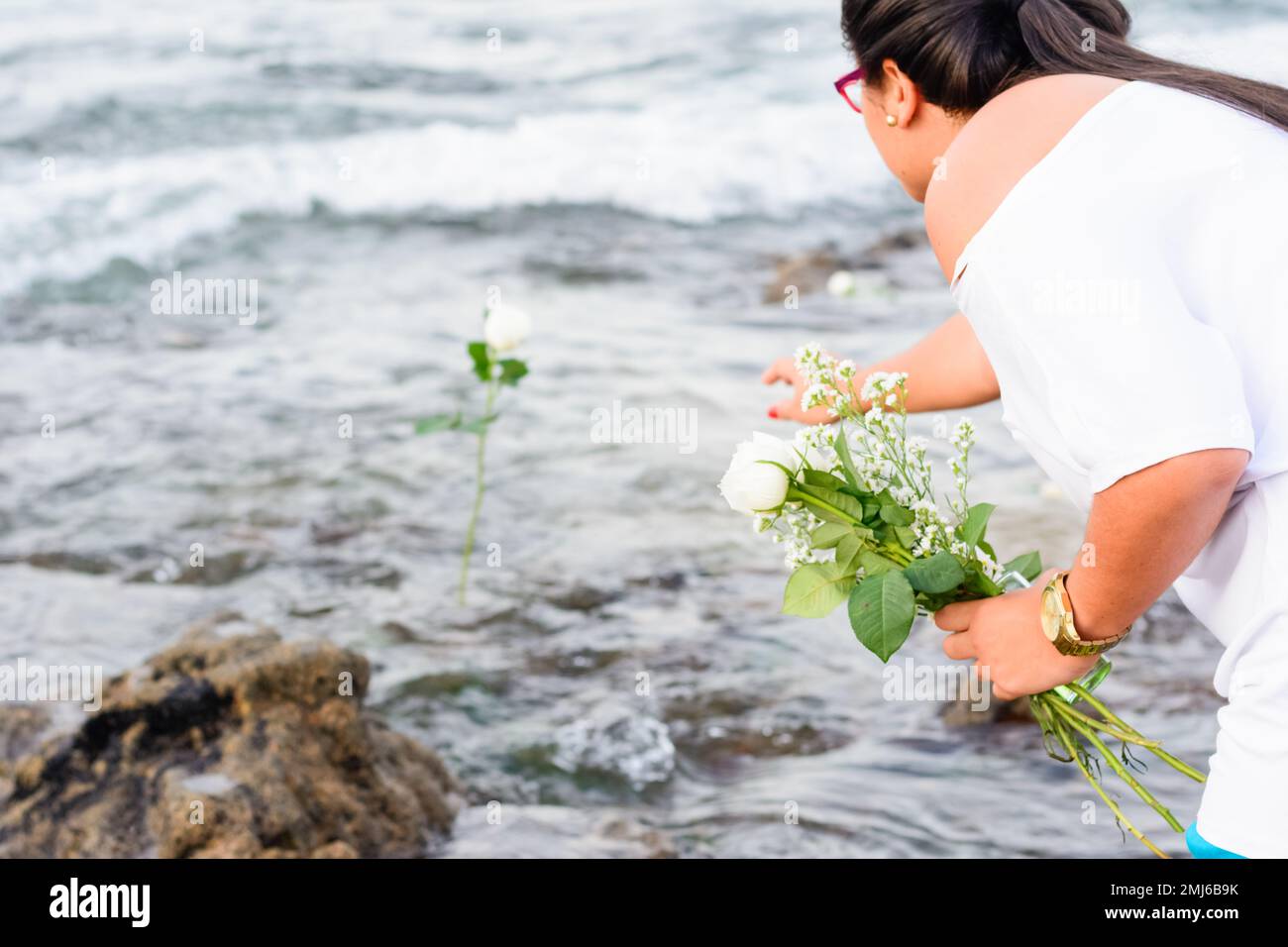 Salvador, Bahia, Brasile - 02 febbraio 2017: Una donna che ammira Candomble getta fiori in mare in onore di Iemanja il giorno della sua festa. Salvador, Foto Stock