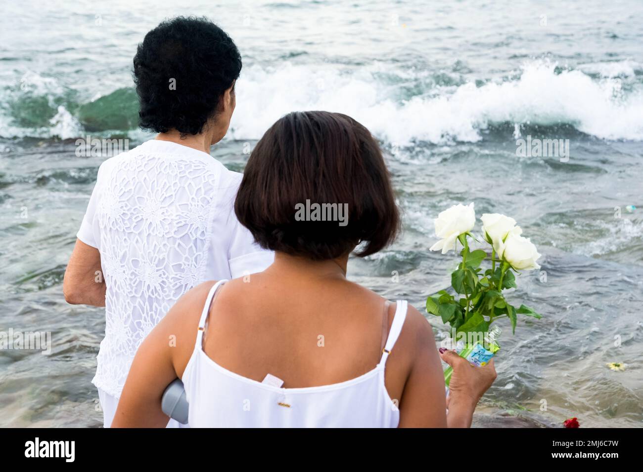 Salvador, Bahia, Brasile - 02 febbraio 2017: Una donna che ammira Candomble getta fiori in mare in onore di Iemanja il giorno della sua festa. Salvador, Foto Stock