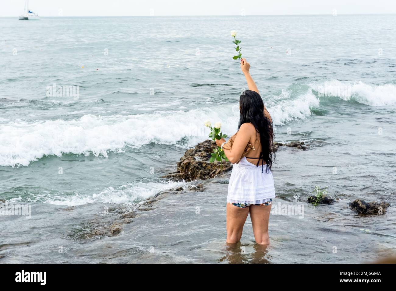 Salvador, Bahia, Brasile - 02 febbraio 2017: Una donna che ammira Candomble getta fiori in mare in onore di Iemanja il giorno della sua festa. Salvador, Foto Stock