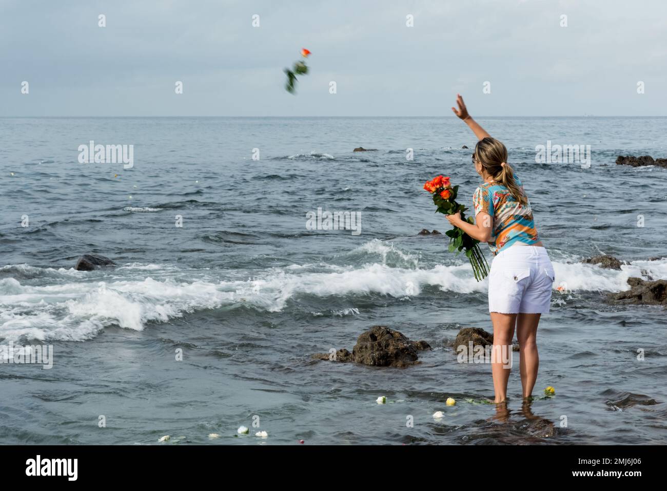 Salvador, Bahia, Brasile - 02 febbraio 2017: Una donna che ammira Candomble getta fiori in mare in onore di Iemanja il giorno della sua festa. Salvador, Foto Stock