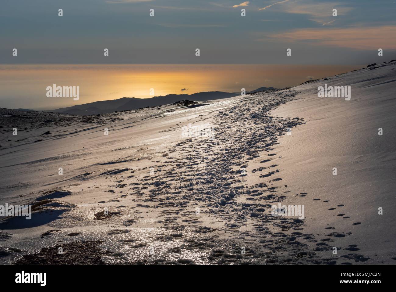 Collina sul lato sud della Sierra Nevada con le tracce degli alpinisti nella neve, sullo sfondo il Mar Mediterraneo con i riflessi Foto Stock