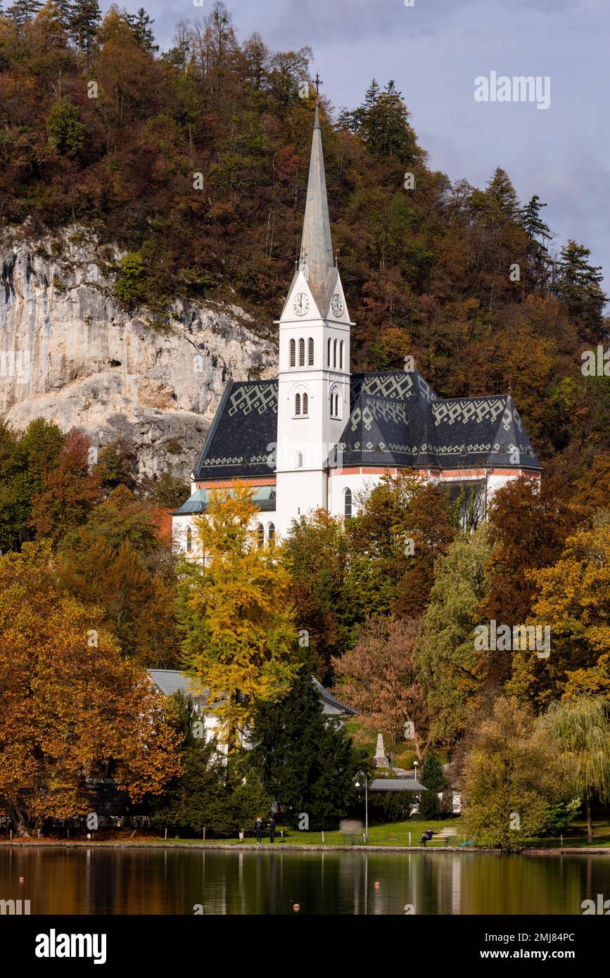 Pittoresca e gotica di St Chiesa Parrocchiale di Martin sulla collina e sulle rive del lago di Bled in Slovenia. Build 1905. Il colò d'autunno giallo e arancione Foto Stock