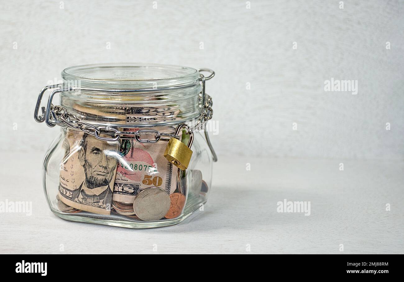 Lucchetto in oro e catena fissati intorno al vasetto di denaro su sfondo grigio chiaro testurizzato Foto Stock