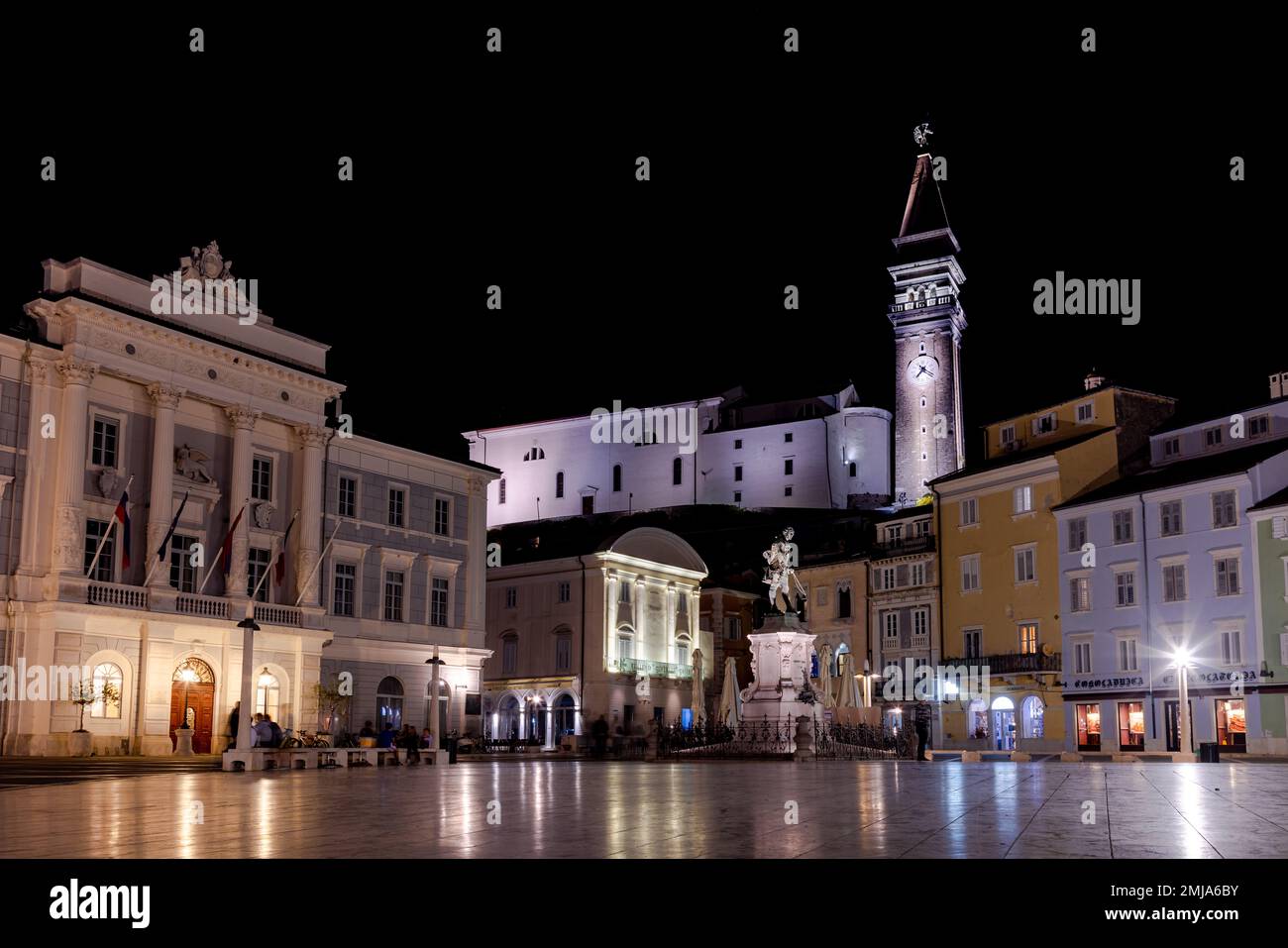 Piran, Slovenia - 14 ottobre 2022: Vista notturna di Piazza Tartini a Piran con architettura colorata, torre della chiesa e turisti. Foto Stock