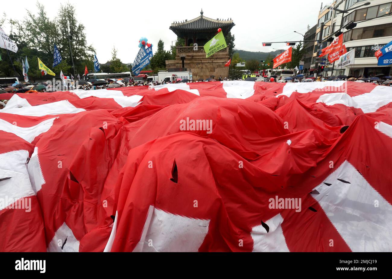 South Korean protesters prepare to tear a Japanese rising sun flag during a rally to mark the South Korean Liberation Day from Japanese colonial rule in 1945, in front of the Japanese Embassy in Seoul, South Korea, Thursday, Aug. 15, 2019. South Korean President Moon Jae-in offered an olive branch to Japan to end an ongoing trade dispute Thursday, saying Seoul will "gladly join hands" if Tokyo wants to talk. (AP Photo/Ahn Young-joon) Foto Stock