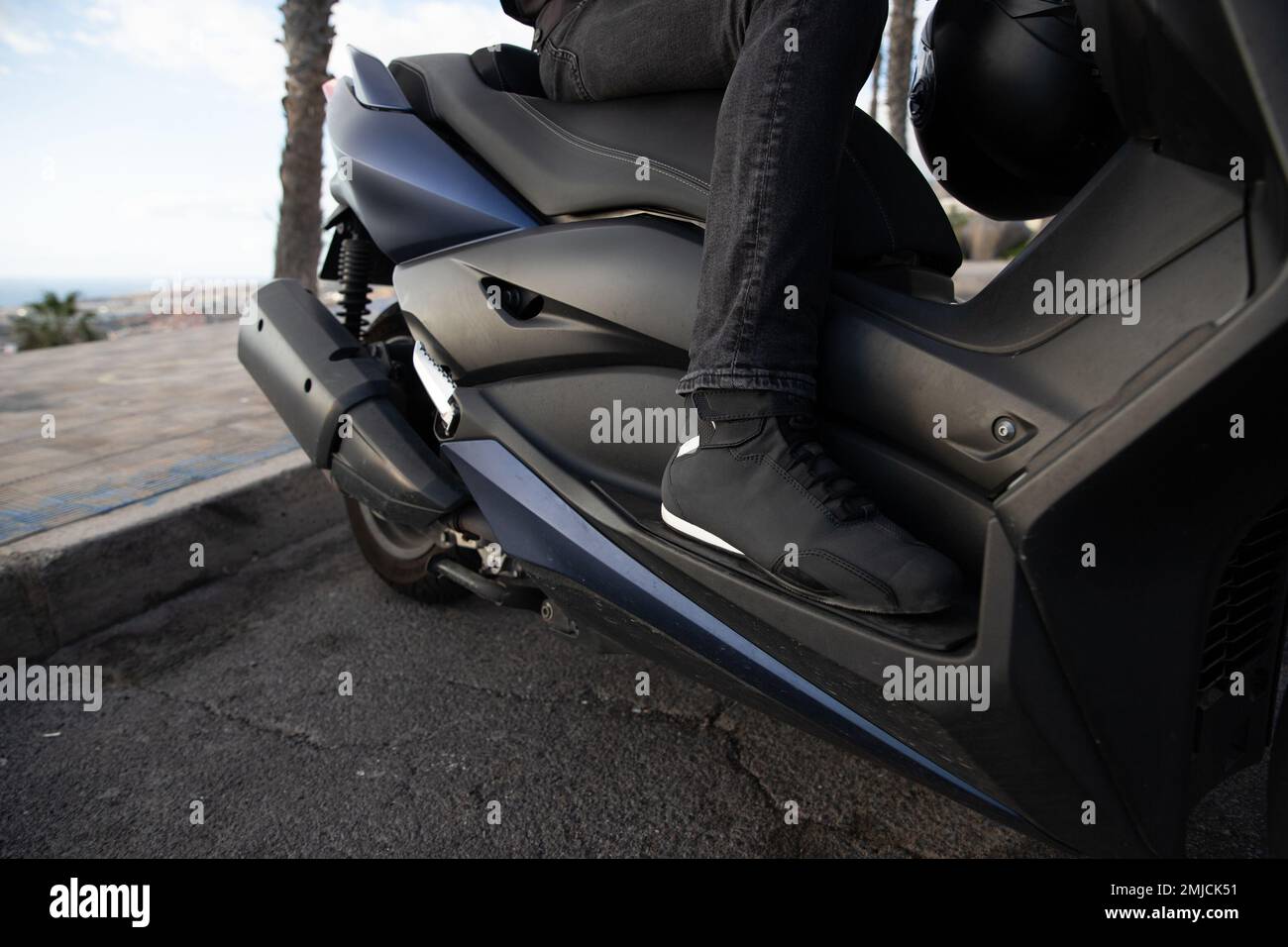 Primo piano delle scarpe protettive di un motociclista che guida sul suo scooter Foto Stock