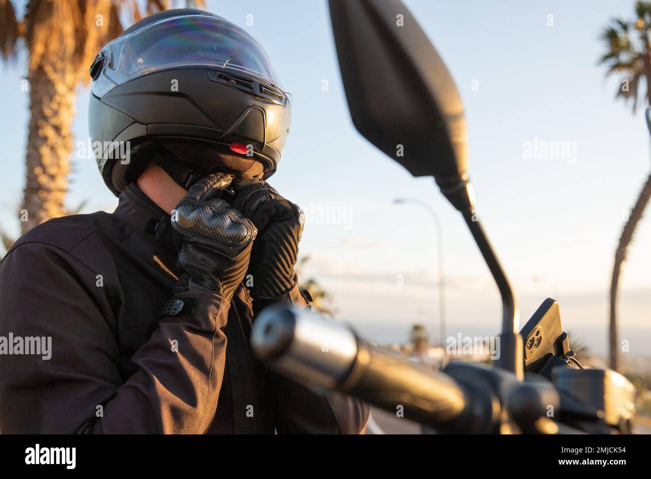 Un motociclista indossa il casco e fissa la cintura di sicurezza, concetto di sicurezza stradale Foto Stock