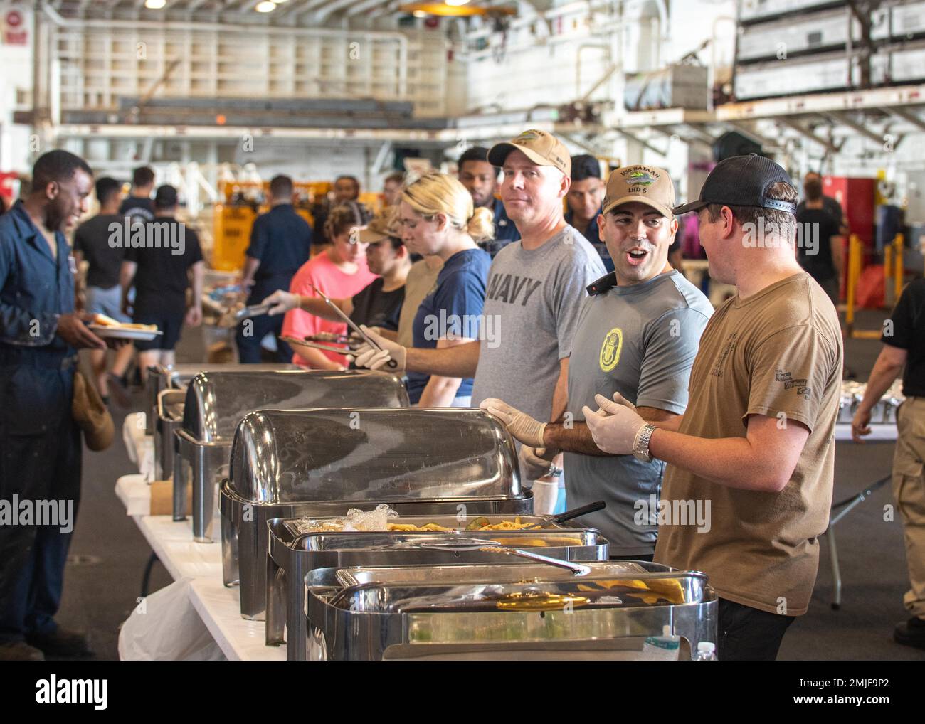 OCEANO ATLANTICO (28 agosto 2022) i membri della nave d'assalto anfibio di classe Wasp USS Bataan (LHD 5) la sala da guerra serve cibo durante un picnic in spiaggia d'acciaio nella baia dell'hangar della nave, 28 agosto 2022. Bataan sta conducendo un'ispezione tecnica del gruppo di formazione a galla come parte del ciclo di formazione della fase di base. Foto Stock