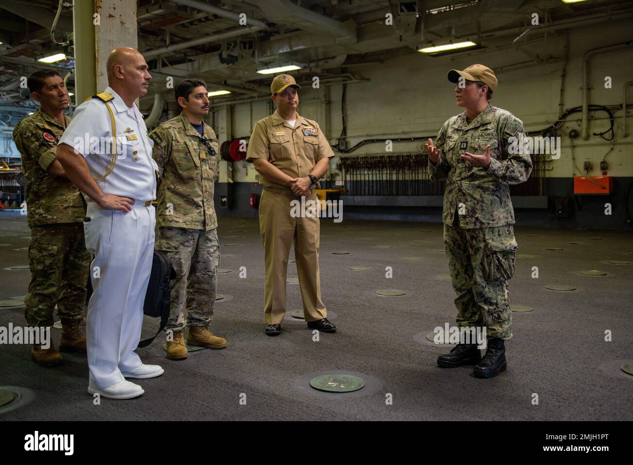 SAN DIEGO (29 agosto 2022) – la Lt. Rebecca Samuels spiega le capacità di spedizione della nave d'assalto anfibio USS Boxer (LHD 4) al Capt. Matthew Cieslukowski, al centro, comandante ufficiale di Boxer, argentino posteriore ADM. Berazay-Martinez, anteriore sinistra, argentino Naval Attaché agli Stati Uniti, E i membri della Marina argentina nel ponte dei pozzi durante un tour di familiarizzazione con la nave, 29 agosto. La delegazione della Marina argentina ha visitato Boxer prima del potenziale incarico di un ufficiale argentino di guerra di superficie a bordo di una nave anfibia attraverso il programma di scambio del personale. Boxer è una classe Wasp Foto Stock