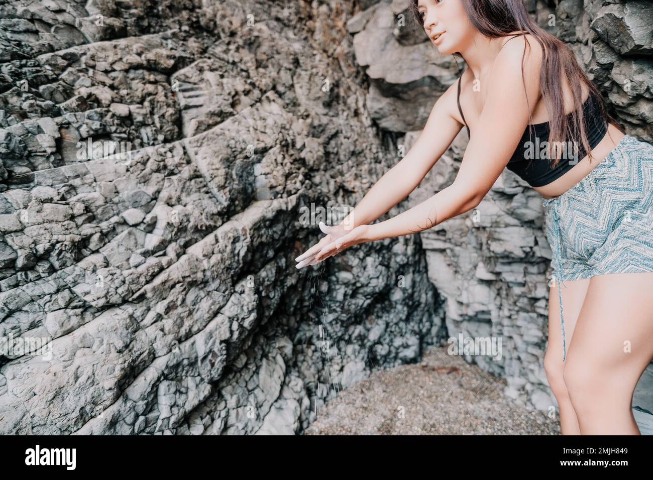 Sport Donna arrampicata sulla roccia. Giovane donna con corpo slim-fit arrampicata in grotta vulcanica basalto con bella vista mare. La ragazza atleta si allena Foto Stock