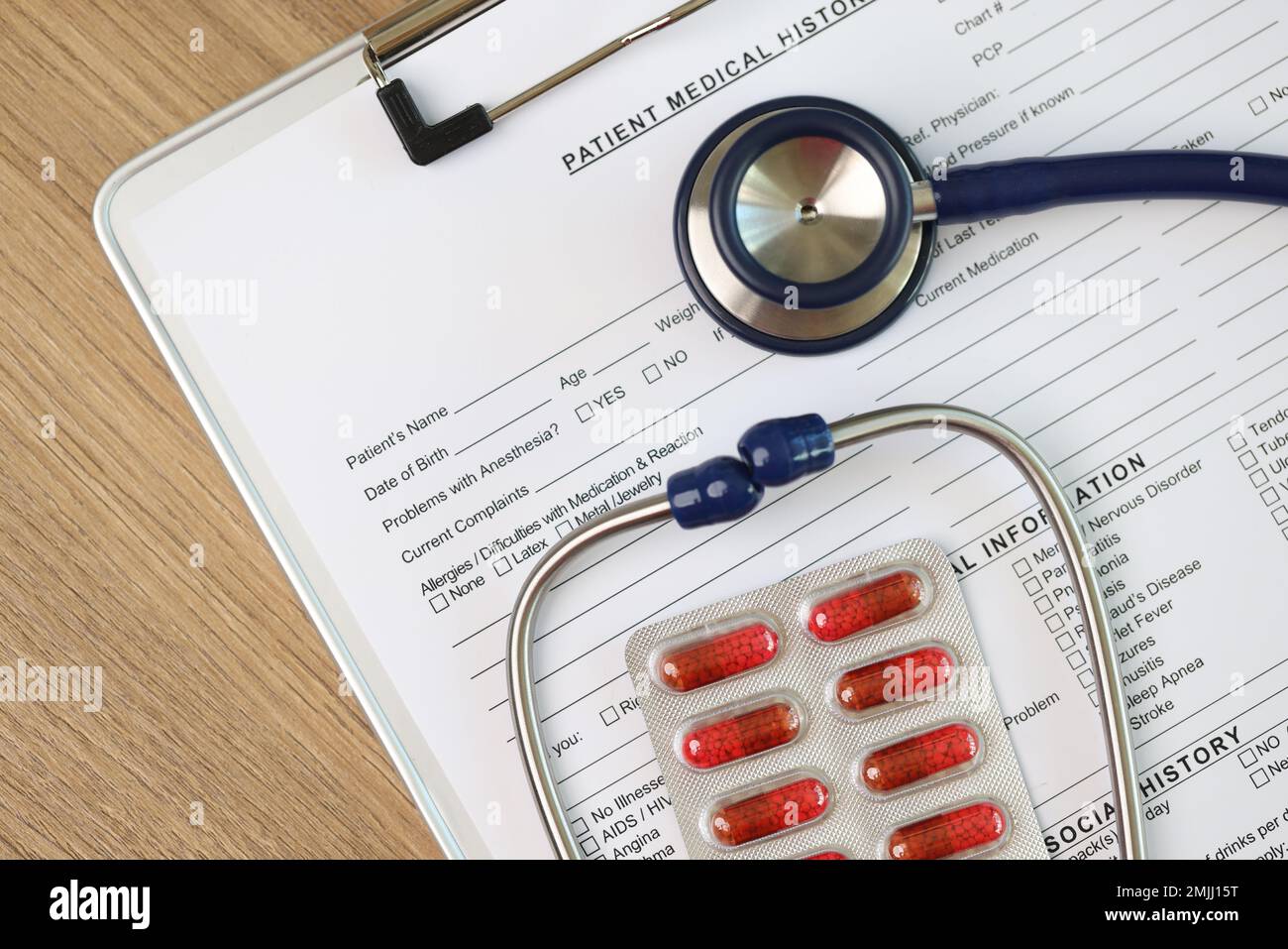 Foglio bianco della forma di anamnesi del paziente con stetoscopio e pillole, vista dall'alto. Foto Stock
