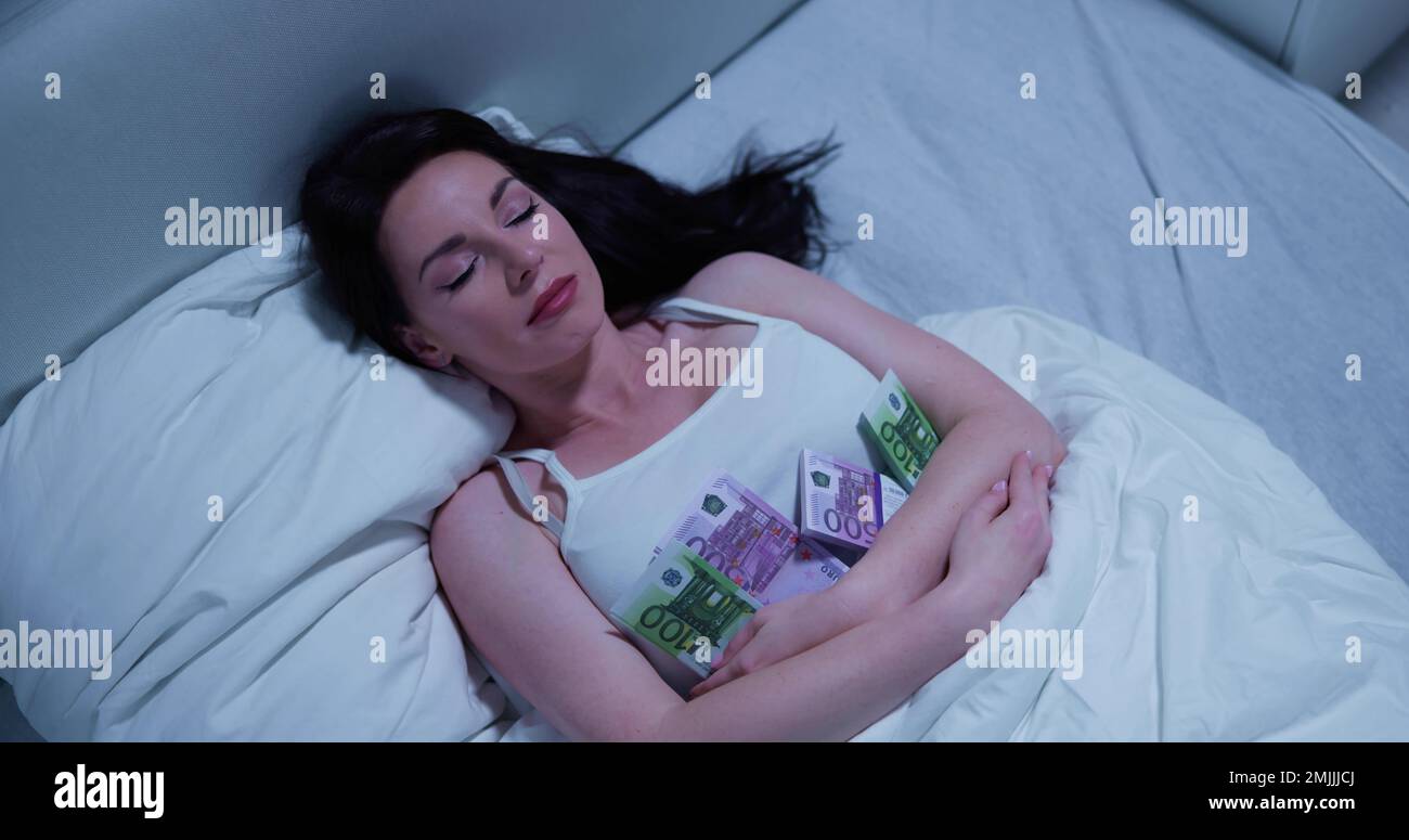 Donna che dorme sul letto con il pacchetto delle note di valuta Foto Stock