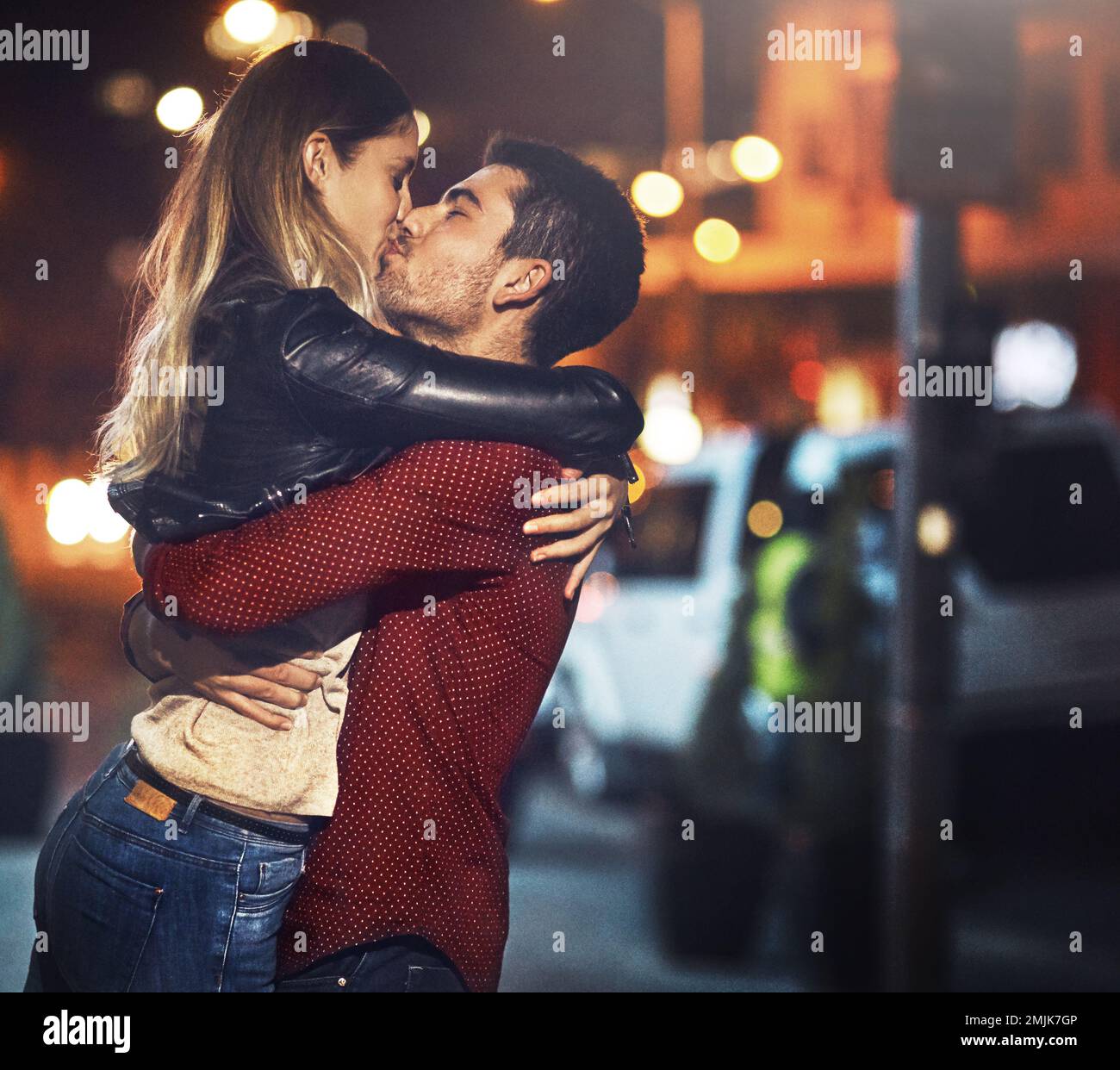 Condividere baci in città. una giovane coppia che condivide un romantico bacio all'aperto di notte. Foto Stock