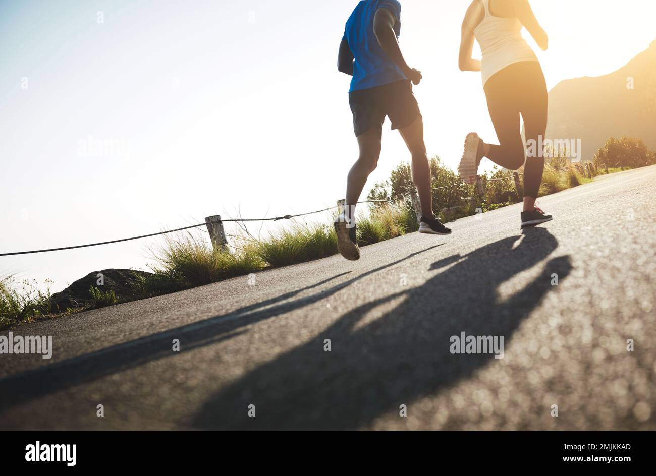 Correre significa essere in forma e mantenere il tuo cuore a pompare. due persone irriconoscibili che corrono su una strada asfaltata. Foto Stock