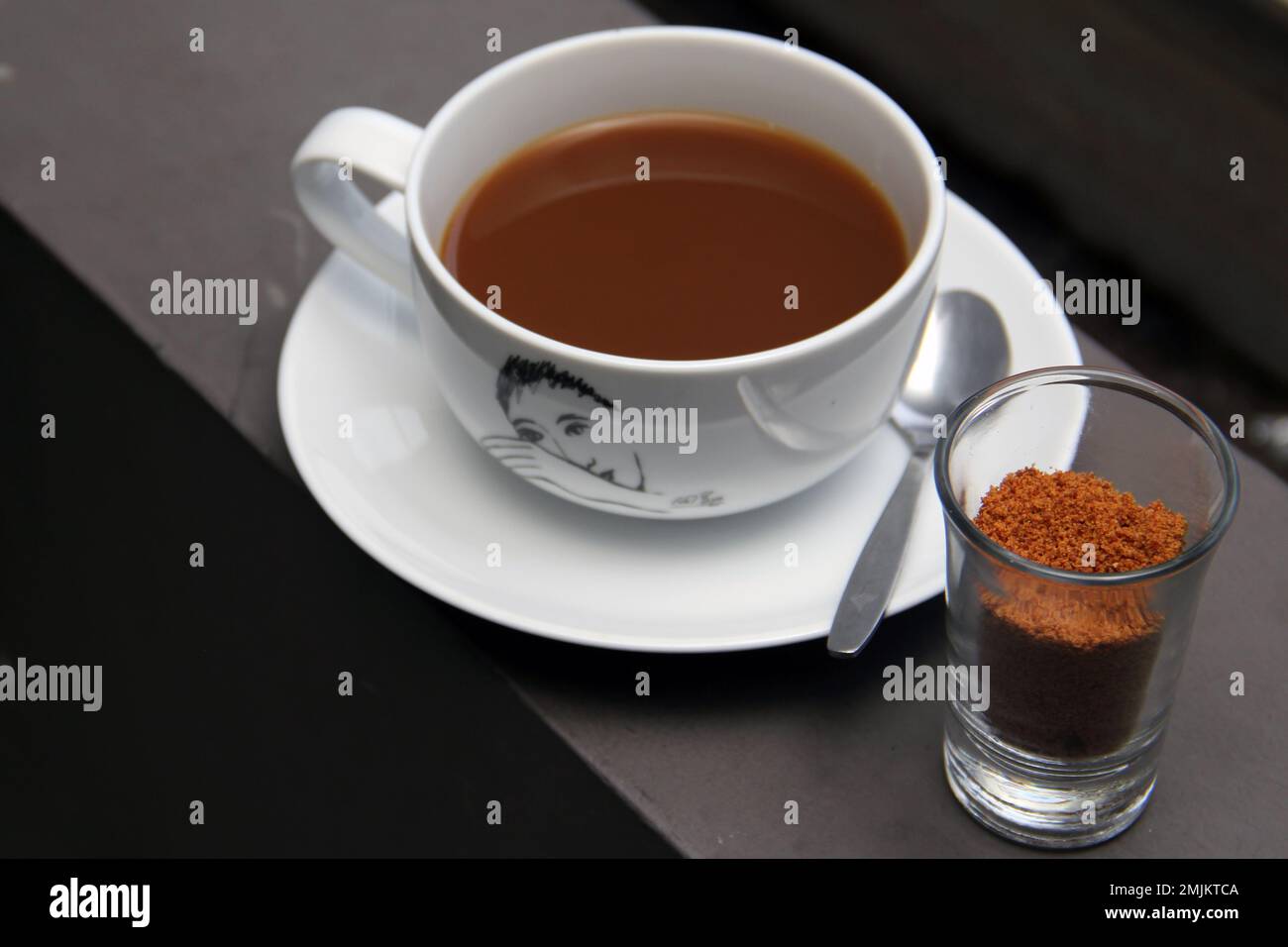 Caffè al latte caldo servito con zucchero di palma in polvere Foto Stock
