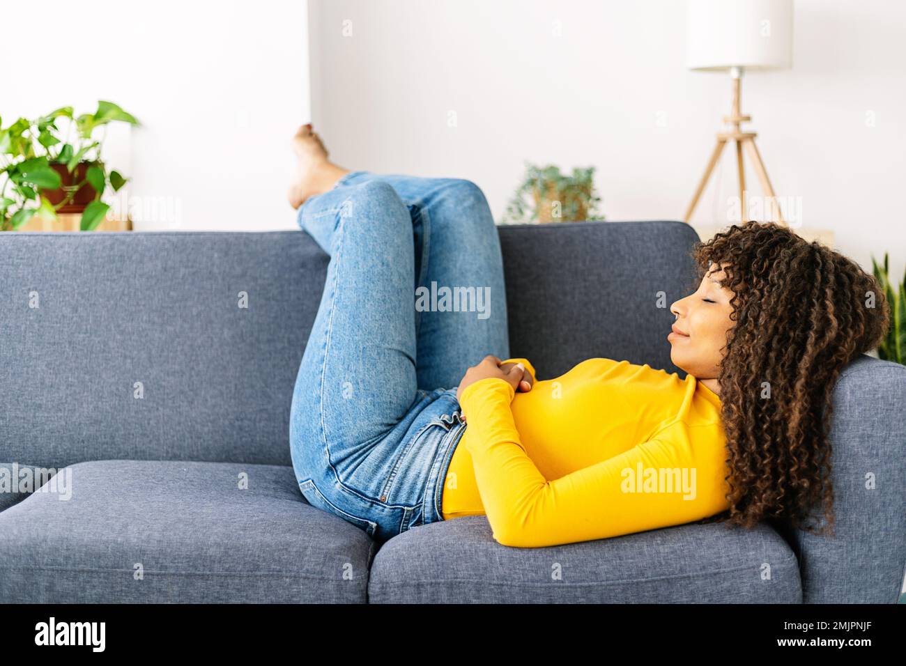 Giovane donna rilassante sul divano di casa Foto Stock