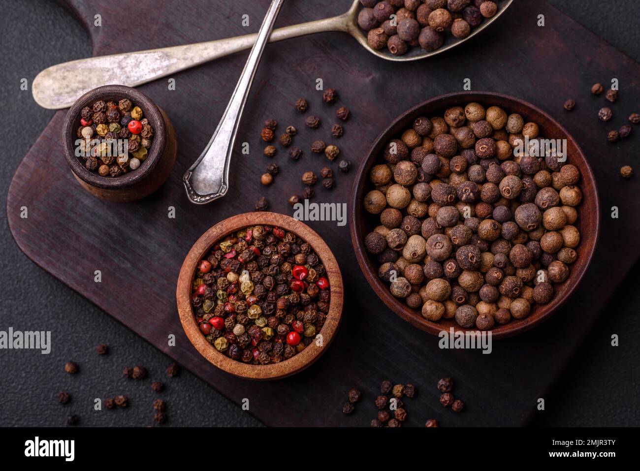 Colore marrone speziato non macinato in un piattino di legno su fondo di cemento scuro Foto Stock