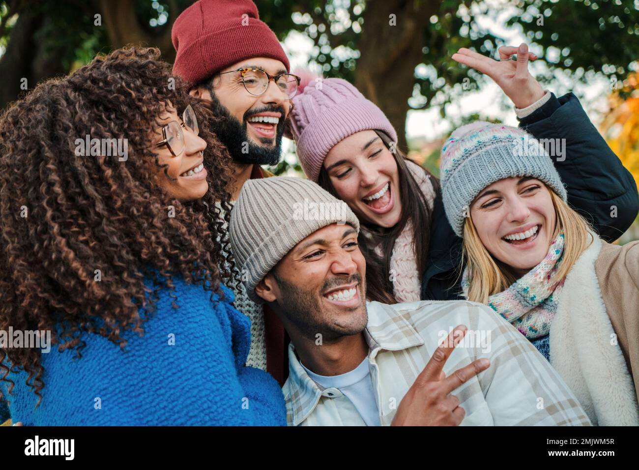 Primo piano ritratto di un gruppo di giovani volti, sorridendo e divertirsi insieme. Amici allegri multirazziali con cappelli, cappotti e abiti autunnali che si godono una giornata del fine settimana. Concetto di stile di vita. Foto di alta qualità Foto Stock