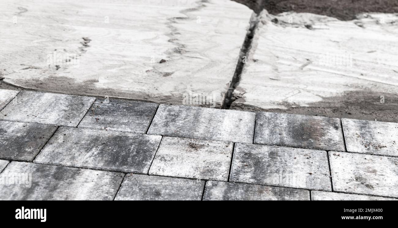 Nuove lastre di pavimentazione grigie, pavimentazione stradale in corso. Foto di sfondo con messa a fuoco selettiva Foto Stock