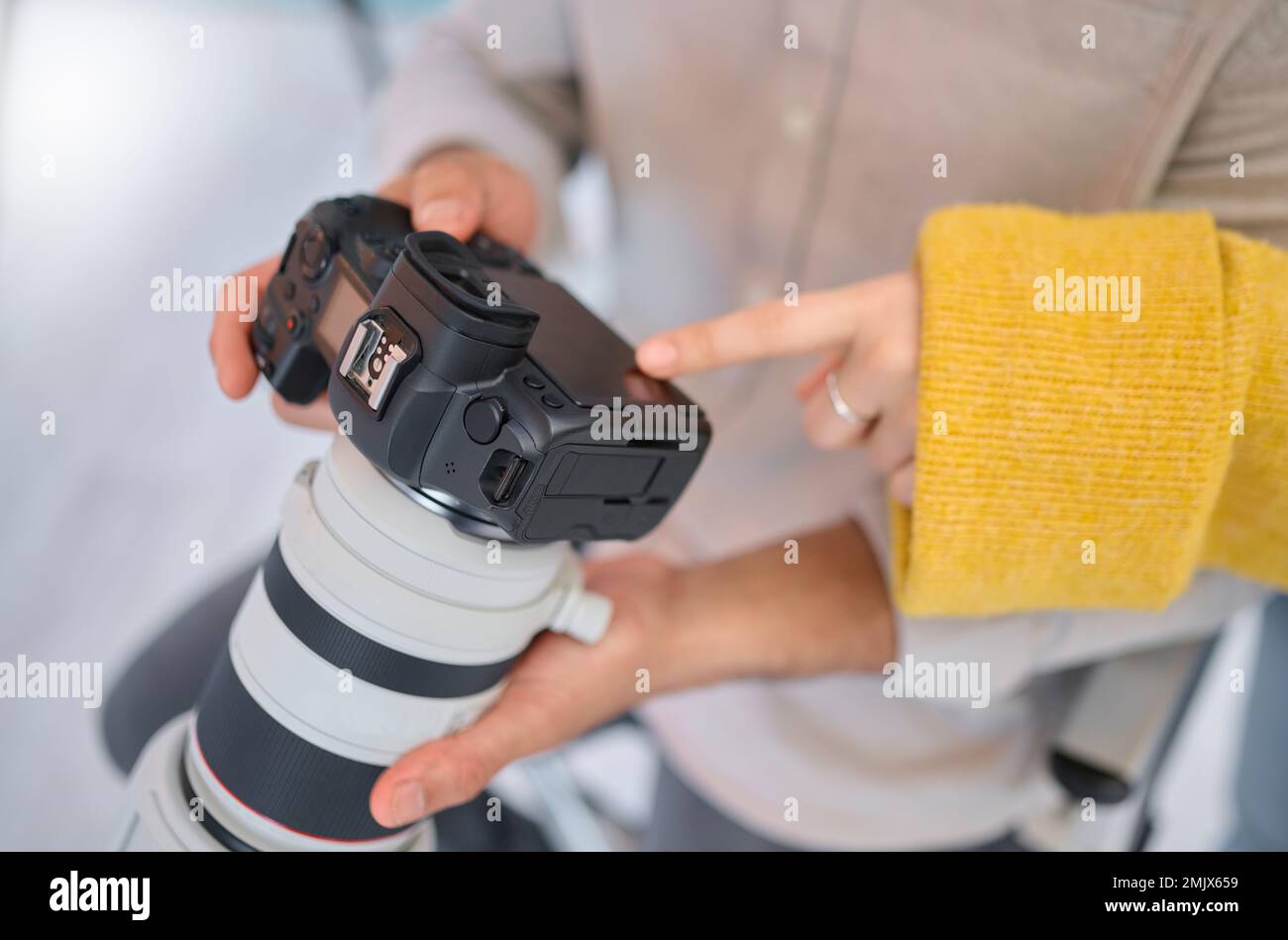 Fotocamera, mani e fotografia per un'agenzia digitale o una società di riviste che si occupa di ambientazione tecnologica. I dipendenti, i modelli e i fotografi esaminano la qualità delle foto Foto Stock