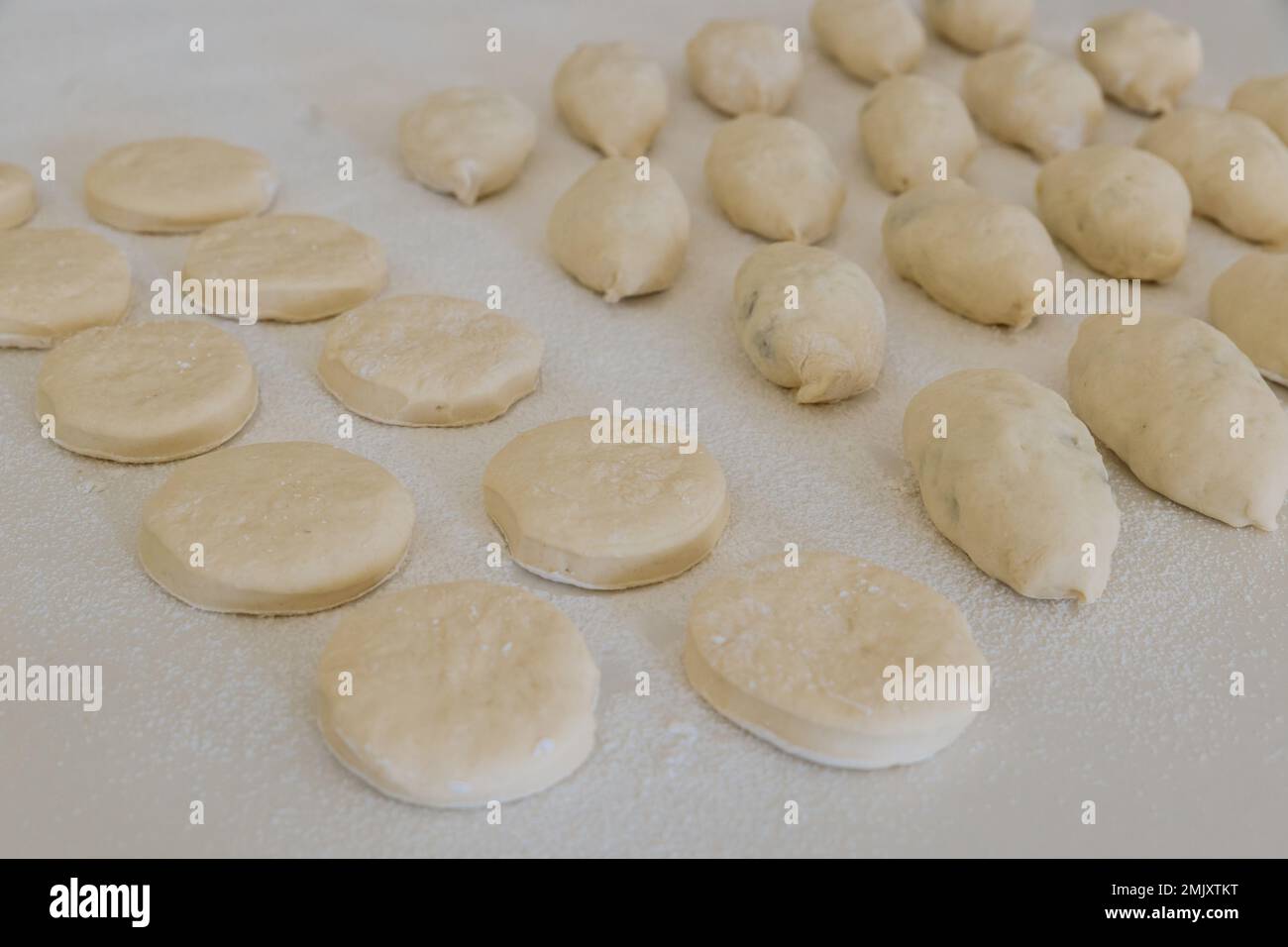 Preparazione per la cottura di ciambelle con ripieno e ciambelle da pasta di lievito su banco bianco Foto Stock