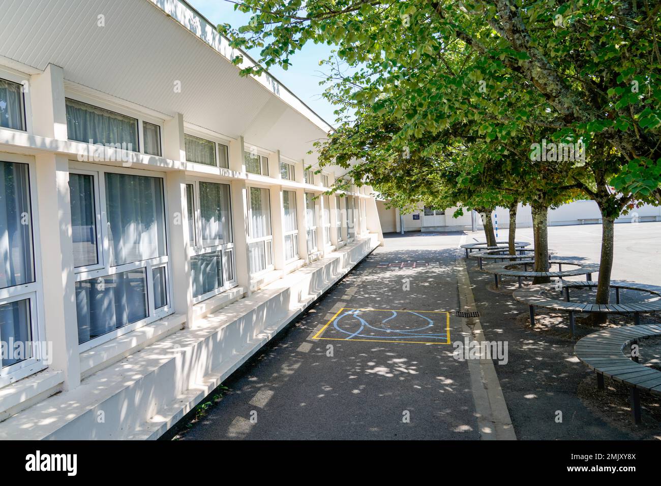 Esterno del cortile della scuola di prescolare con parco giochi e albero Foto Stock