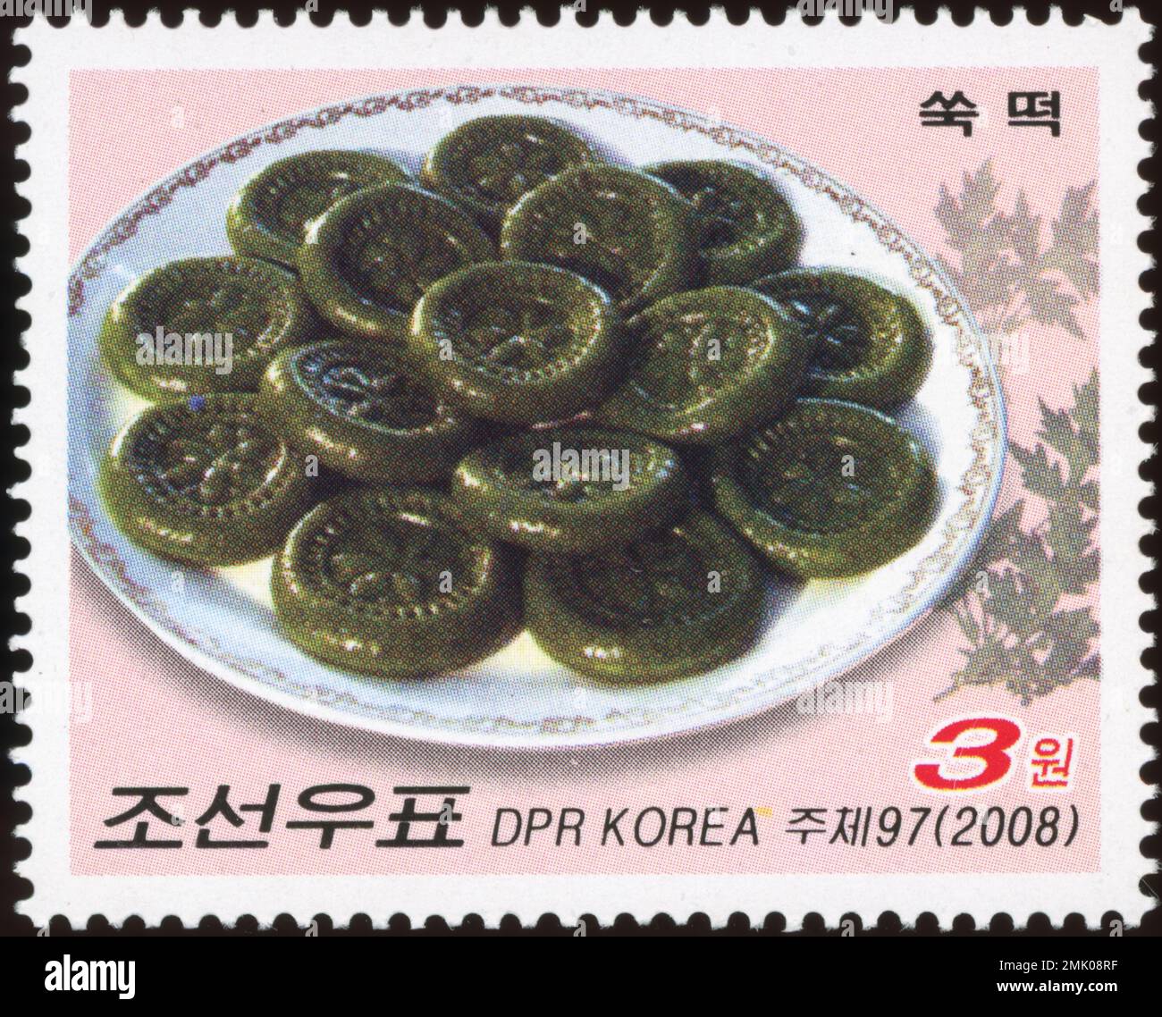 Francobollo nordcoreano del 2008 con tradizionali torte di riso Ssuk-tteok mugwort su un piatto. Foto Stock