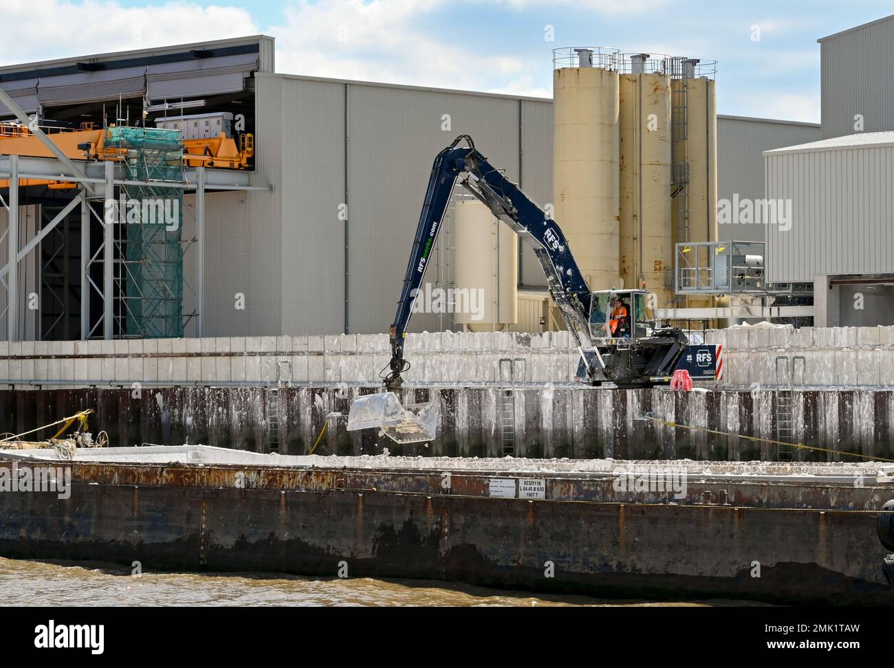 Londra, Regno Unito - 2022 agosto: Persona che gestisce una gru con una fibbietta da afferrare per scaricare rifiuti da una chiatta industriale sul Tamigi Foto Stock