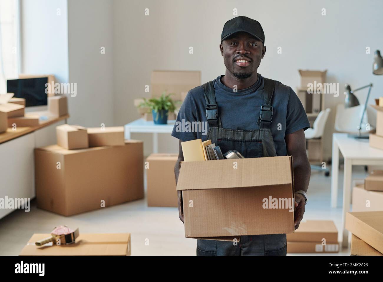 Ritratto del caricatore afro-americano sorridendo alla scatola di presa  della macchina fotografica con le cose, aiutante a muoversi ad un nuovo  ufficio Foto stock - Alamy