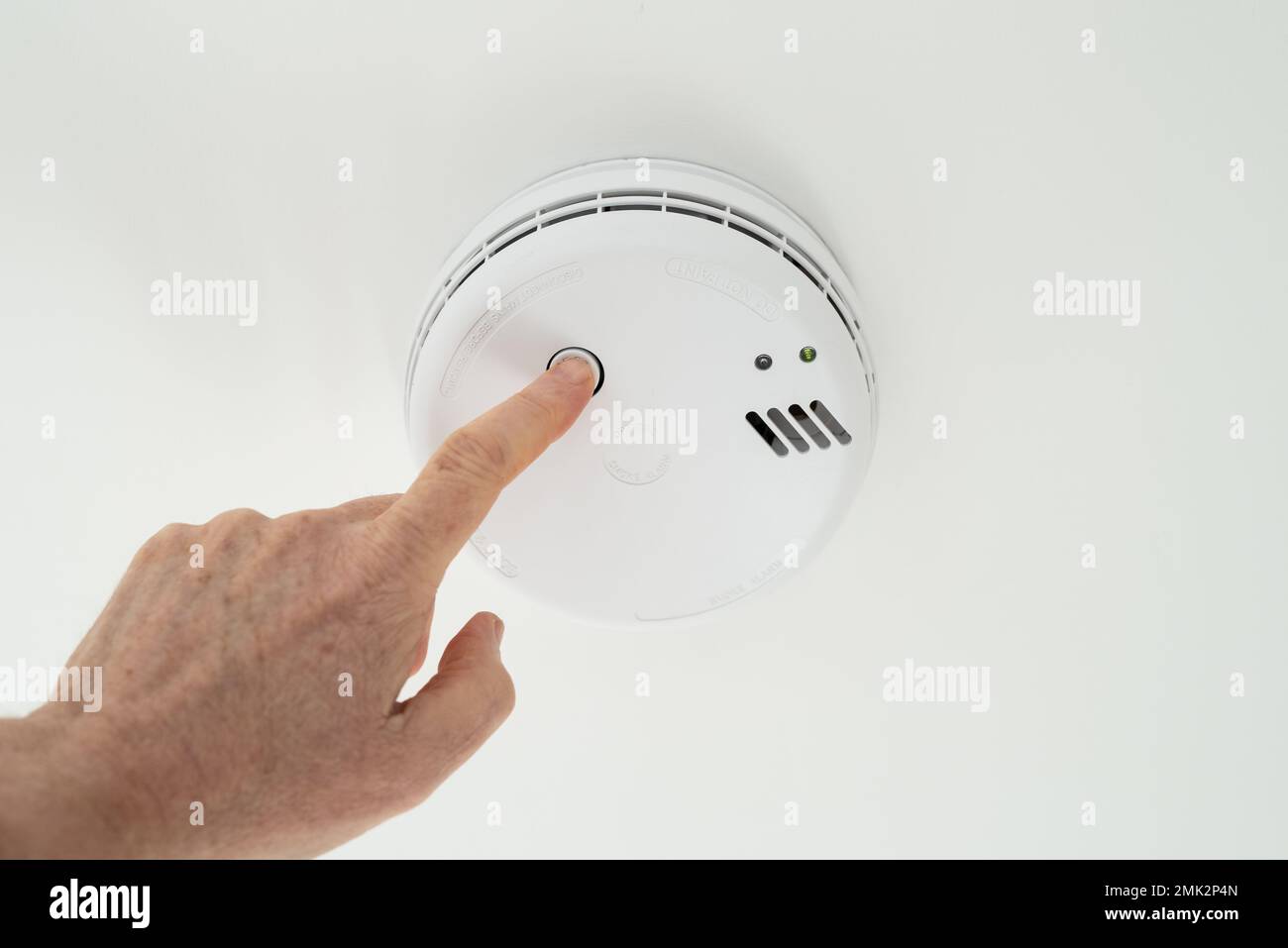 Il proprietario di casa ha visto eseguire un test settimanale su un allarme di fumo montato a soffitto situato nel corridoio di una casa. Foto Stock