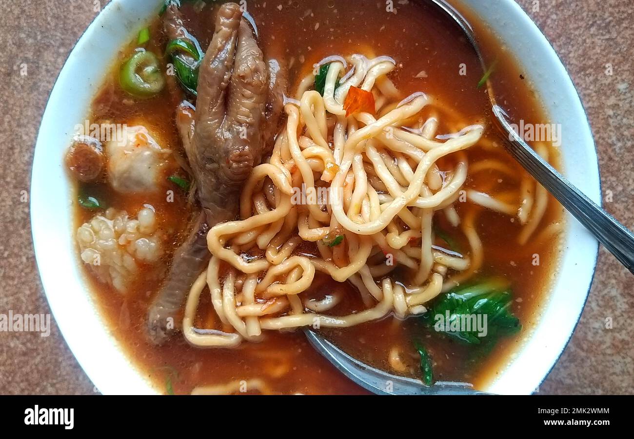cibo sotto forma di zuppa di noodle con un misto di pollo e vari condimenti su di esso Foto Stock