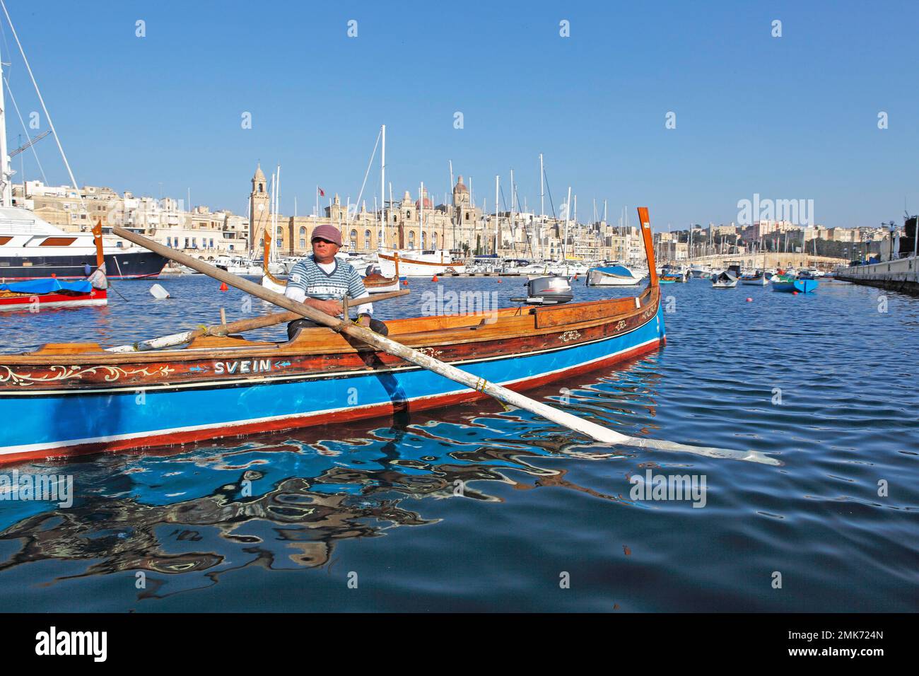 Barca tradizionale o dghajsa a Grand Harbour, Torrente Vittoriosa con Chiesa di San Lorenzo dietro, tre Città, Isole Maltesi Foto Stock