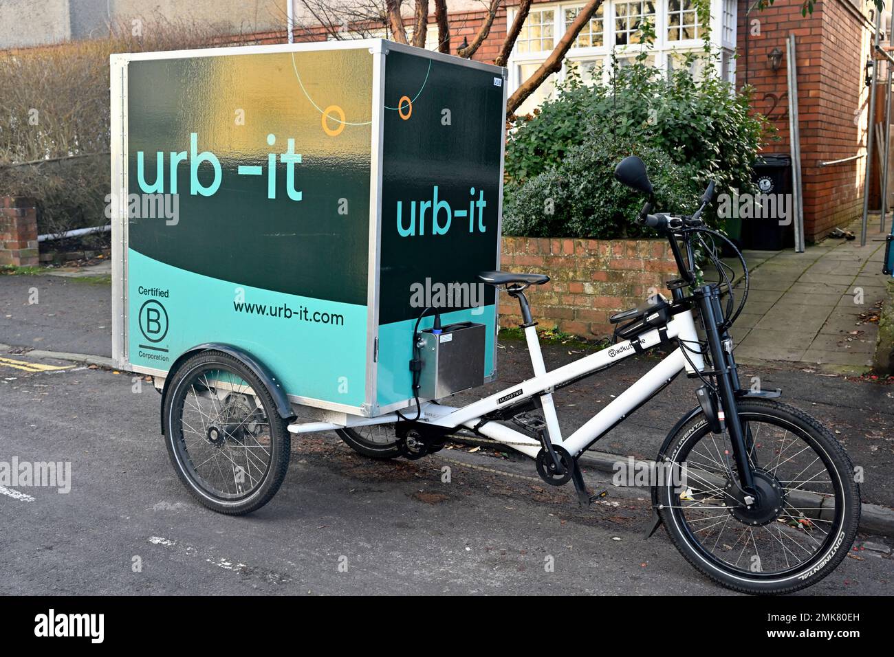 Bici da carico utilizzata per la consegna di pacchi con corriere ciclistico urb-IT di fronte alle case, Inghilterra Foto Stock