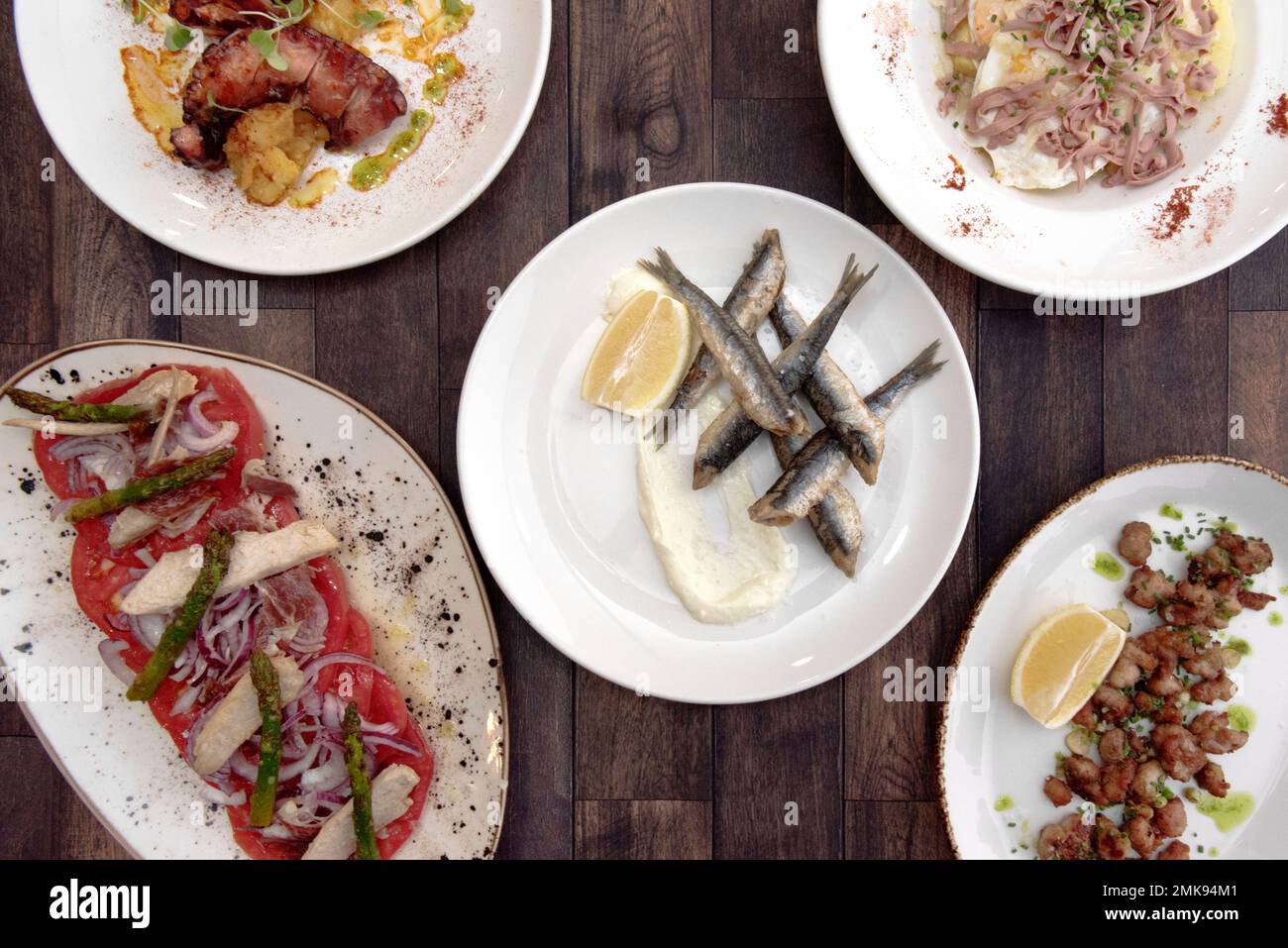 Ottime tapas spagnole con acciughe fritte con maionese, criadilla fritte, polpo galiziano e insalata di pancia di tonno con pomodoro e cipolla Foto Stock