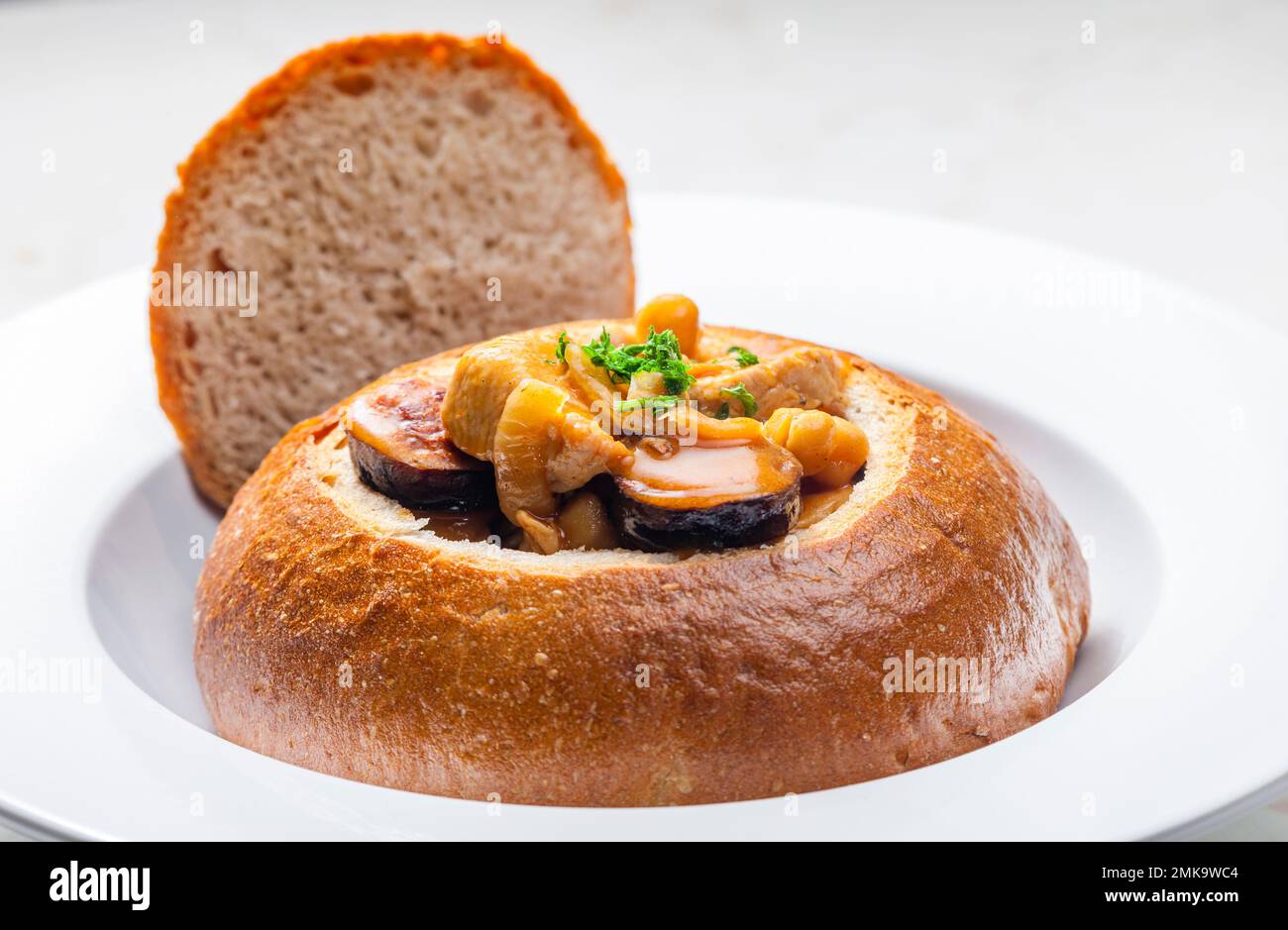 stufato con carne di maiale, ceci e sausge in pane Foto Stock