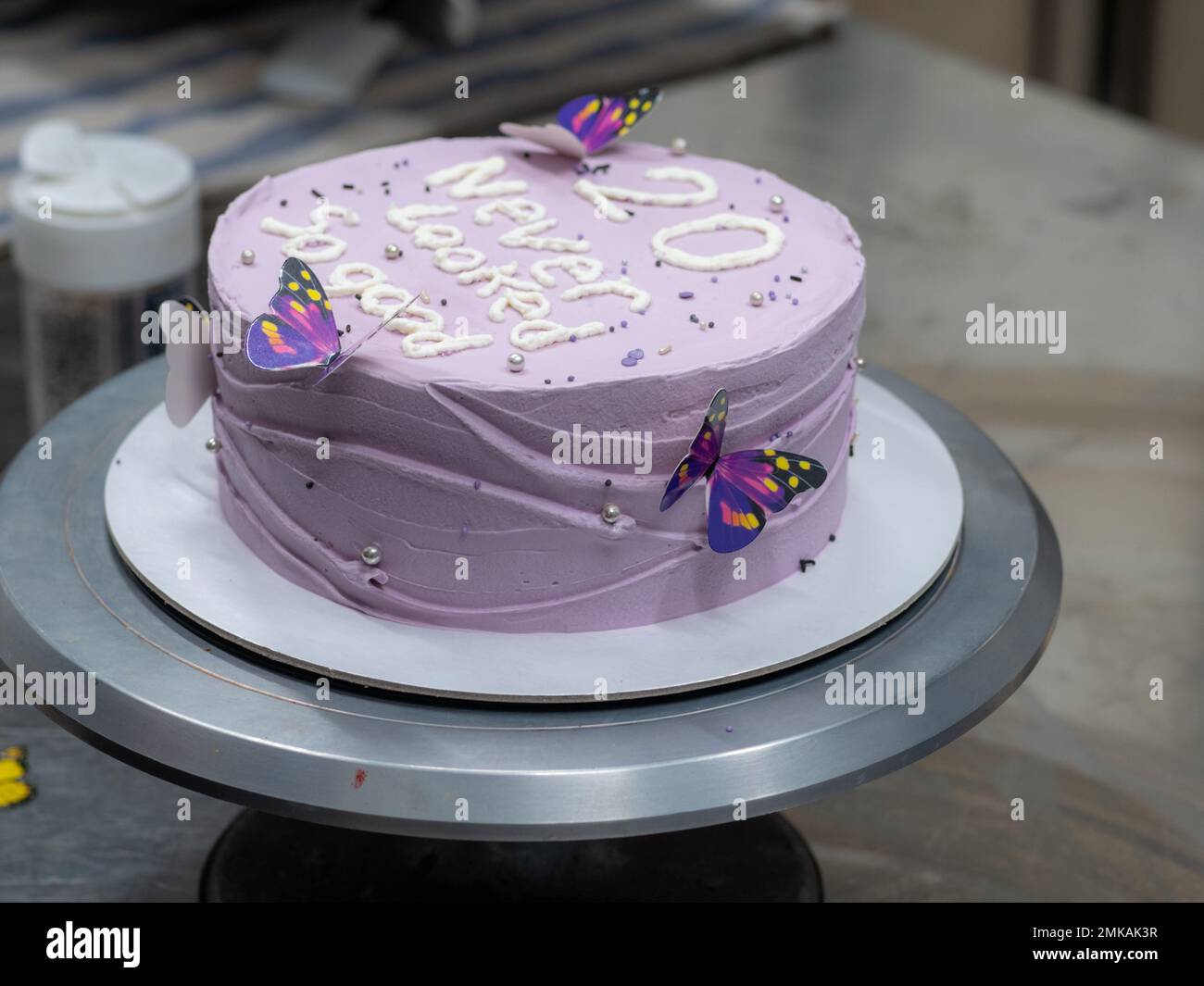 torta ghiacciata di 20 anni decorata con una frase crema fatta a mano, farfalle, perle, spolverate da designer panettiere Foto Stock