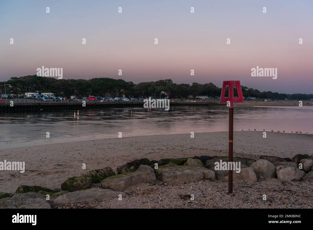 Tramonto dal cielo rosa sul lungomare di Mudeford con vista verso Christchurch Bay durante la bassa marea, Hengistbury Head, Dorset, Inghilterra, Regno Unito Foto Stock