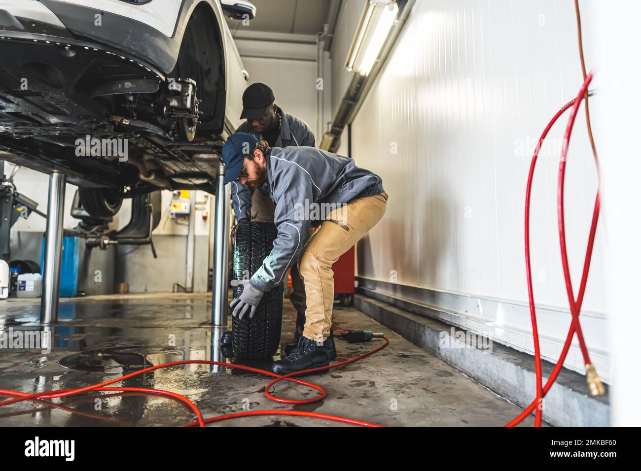 I meccanici dell'automobile sono occupati sostituire le ruote di un'automobile sull'ascensore in un negozio di riparazione auto. Foto di alta qualità Foto Stock