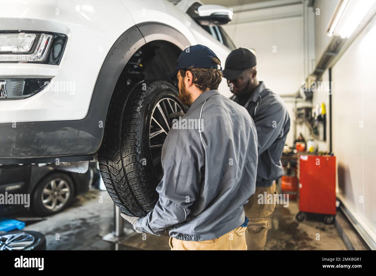 I meccanici dell'automobile sostituiscono le ruote di un'automobile sollevata in una stazione di servizio di riparazione. Foto di alta qualità Foto Stock