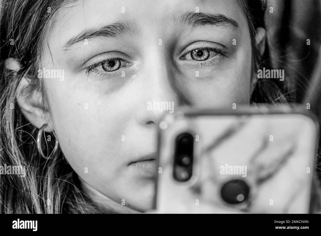 Una ragazza adolescente guarda uno smartphone e grida. Ragazza triste con lacrime negli occhi. Foto Stock